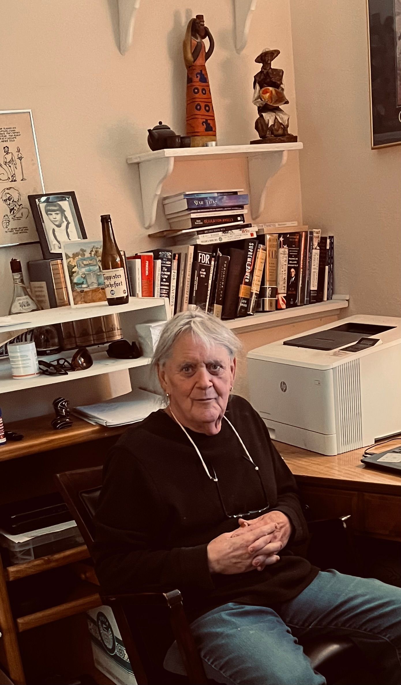 A woman is sitting in a chair in front of a desk.