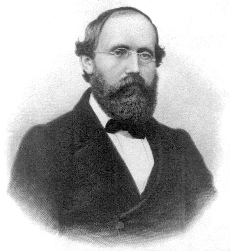 A man with a beard and glasses is wearing a tuxedo and bow tie.