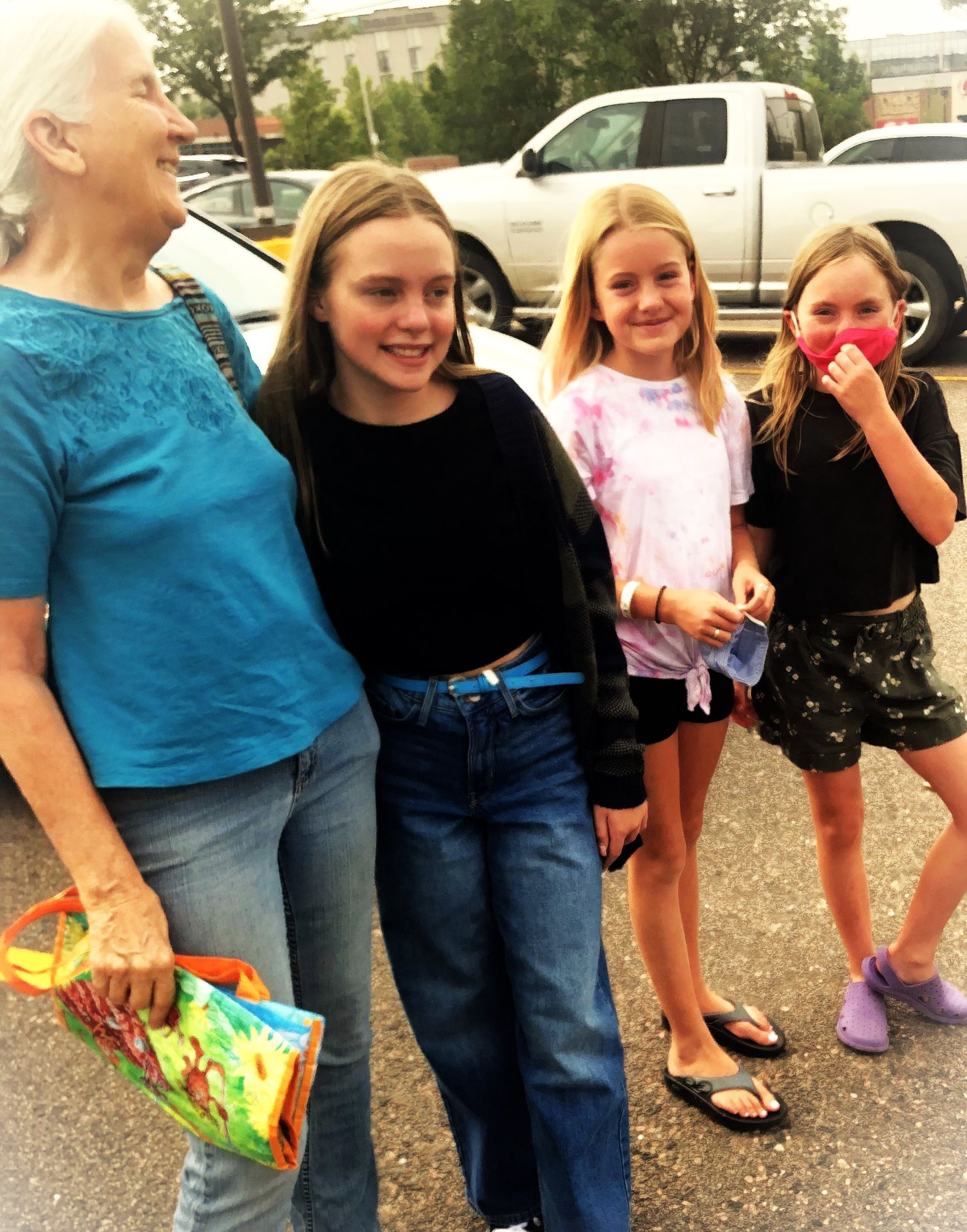A group of young girls are posing for a picture in a parking lot