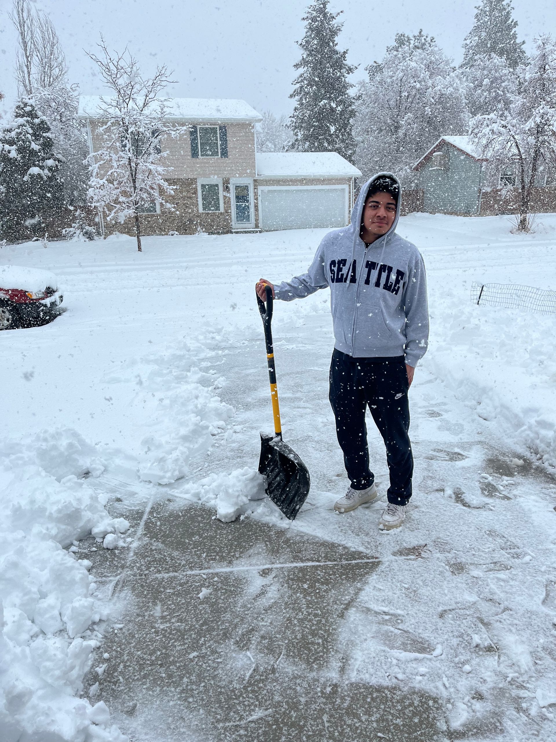 A man is shoveling snow from a driveway with a shovel.