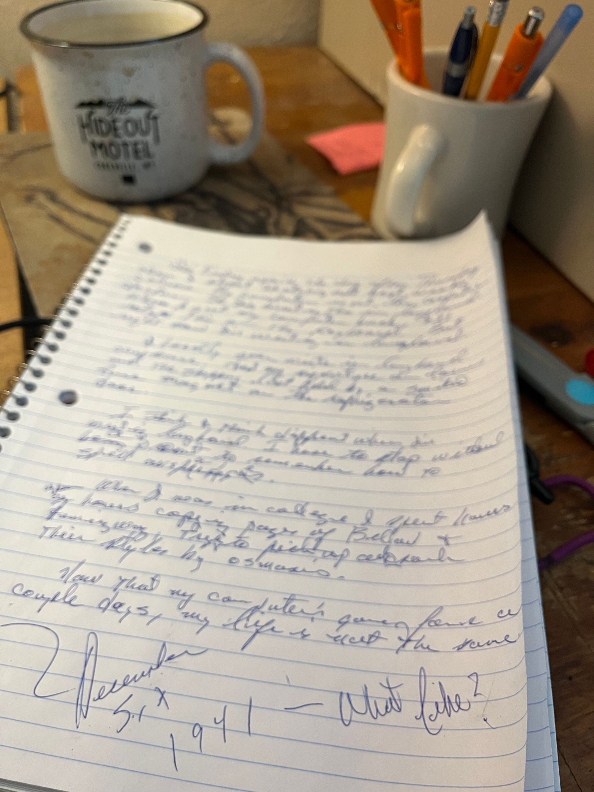 A mug that says kick out notes sits next to a notebook