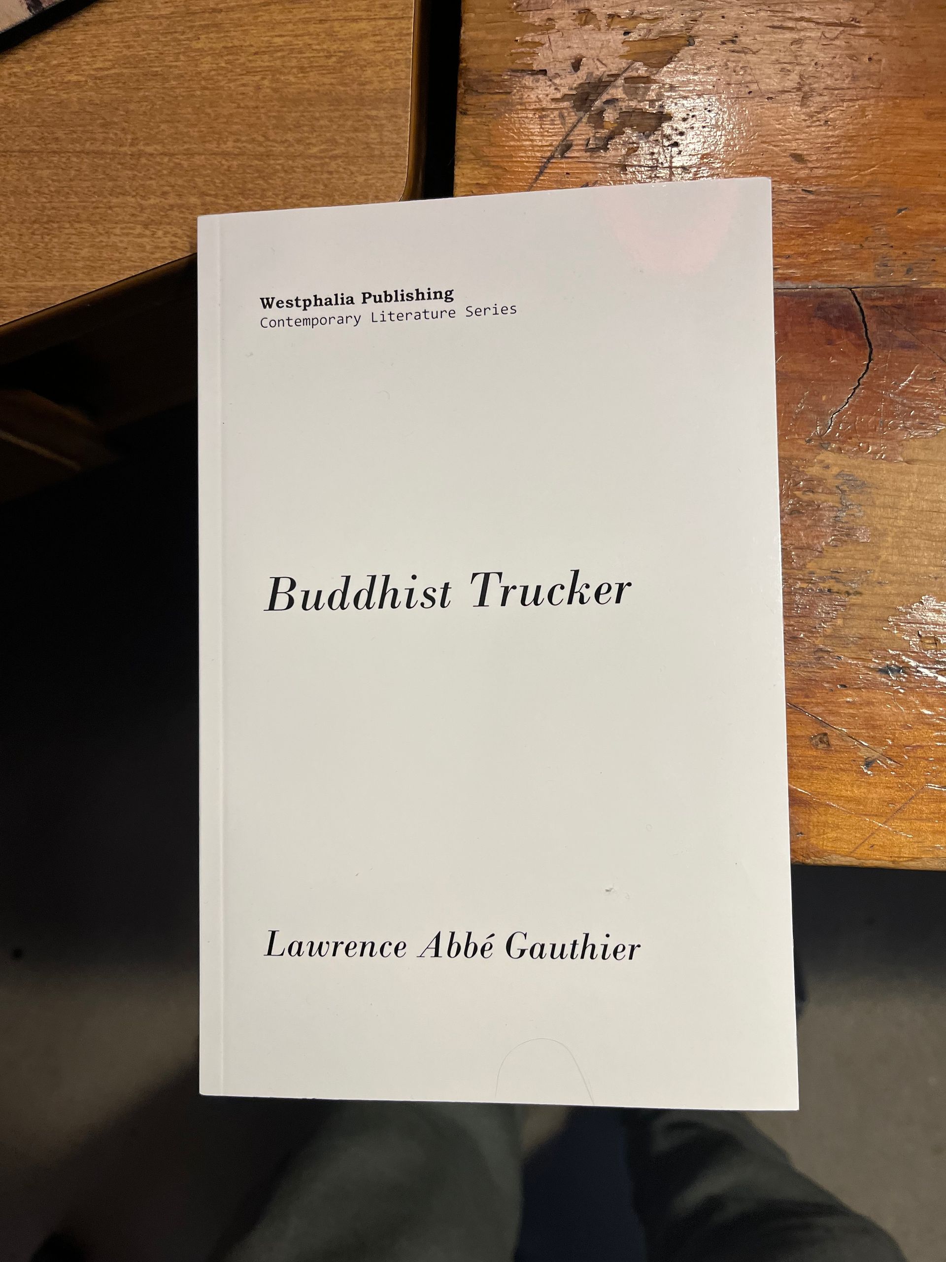 A book titled buddhist trucker sits on a wooden table