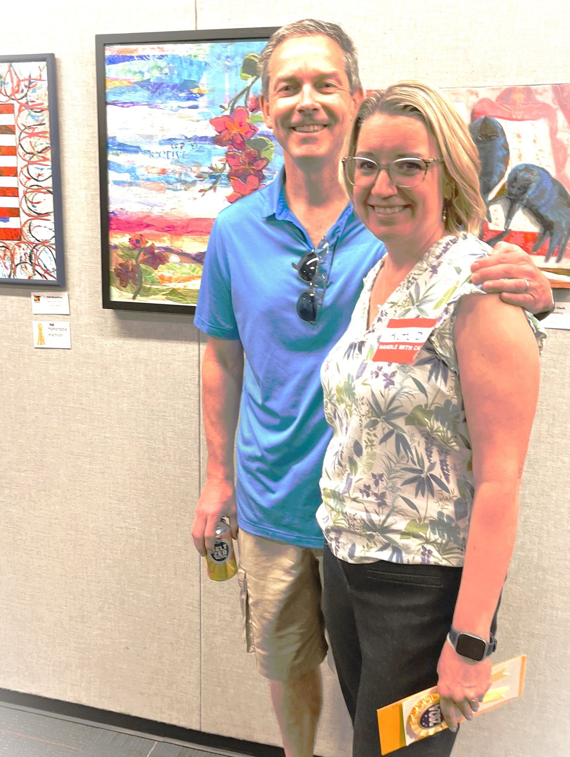 A man and a woman are posing for a picture in front of a painting.