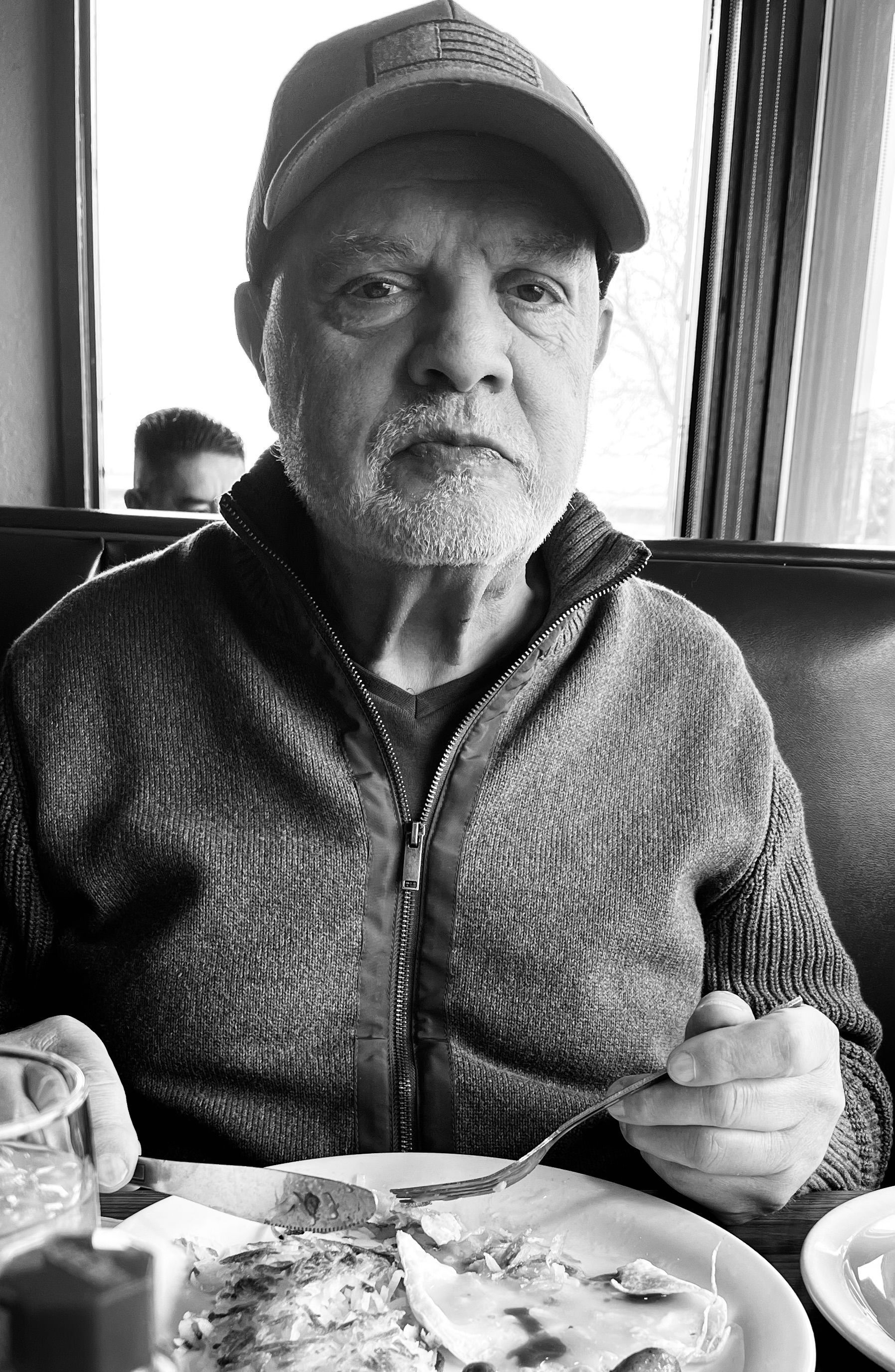 A man is sitting at a table eating a plate of food.