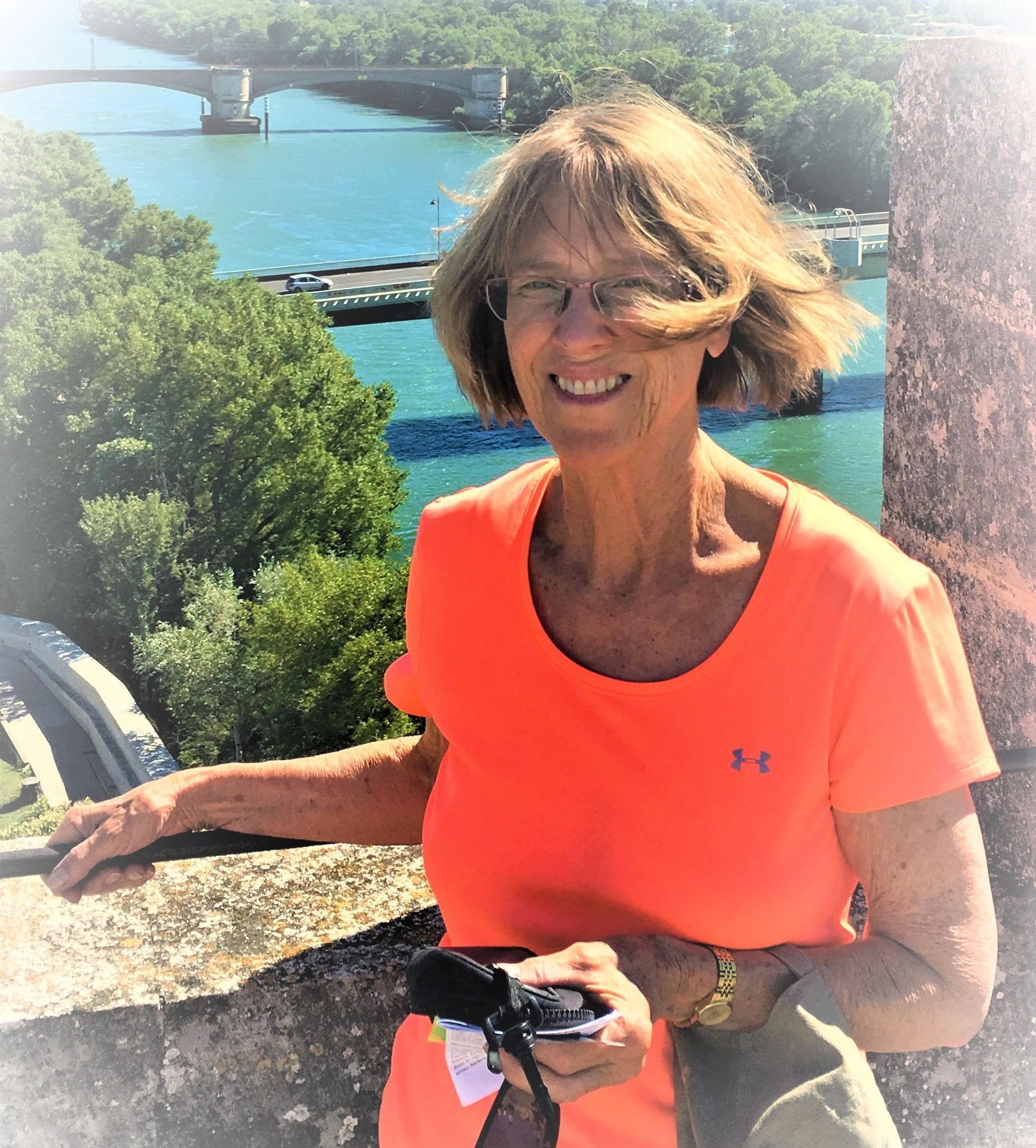 A woman wearing an orange under armour shirt is smiling