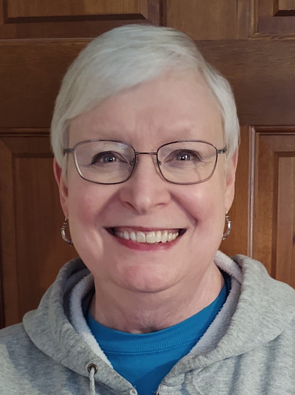 A woman wearing glasses and a blue shirt is smiling for the camera.