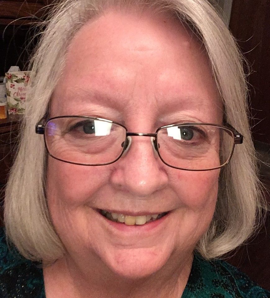 A close up of a woman wearing glasses and smiling.