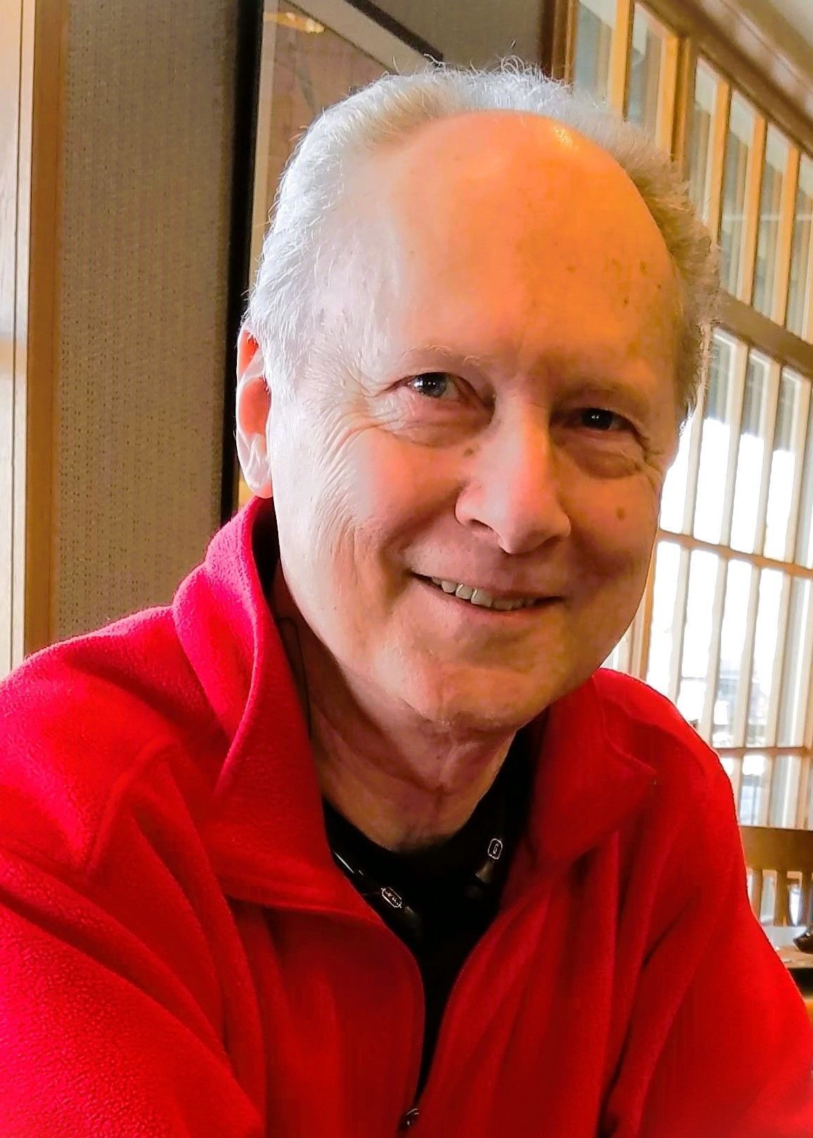 A man wearing a red jacket is smiling for the camera.