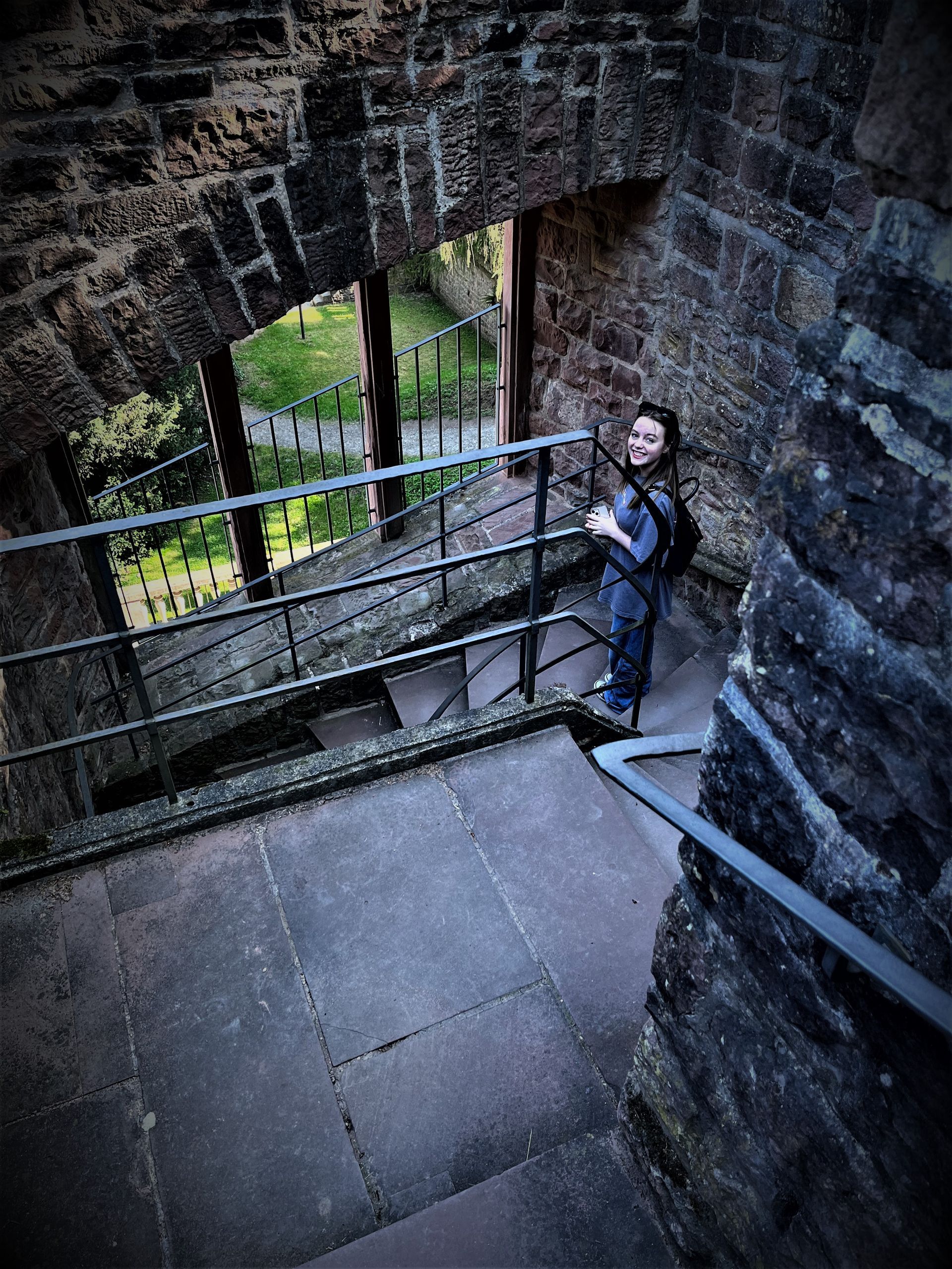 A man is standing on a set of stairs next to a brick wall.
