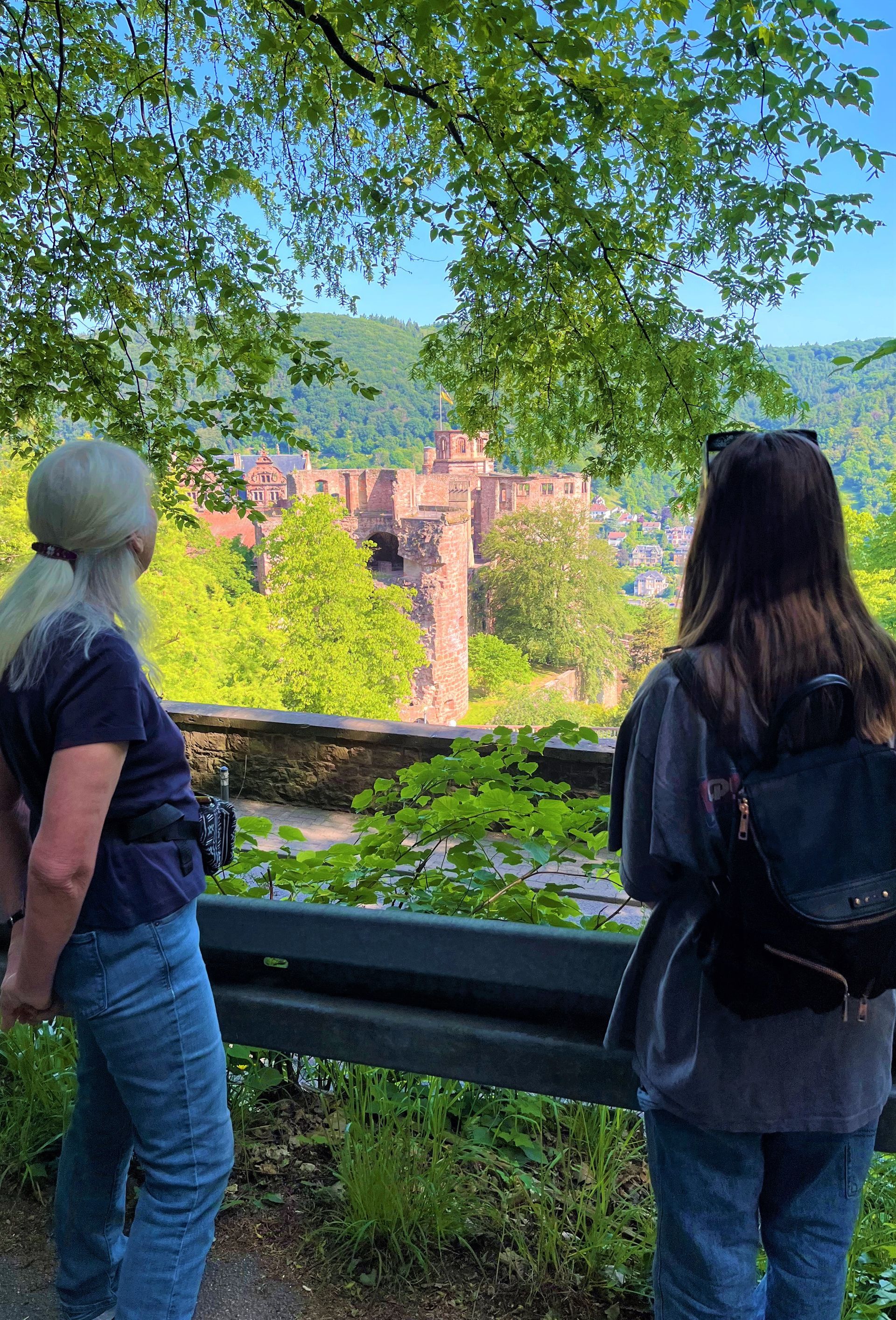 Two women are standing next to each other looking at a castle.