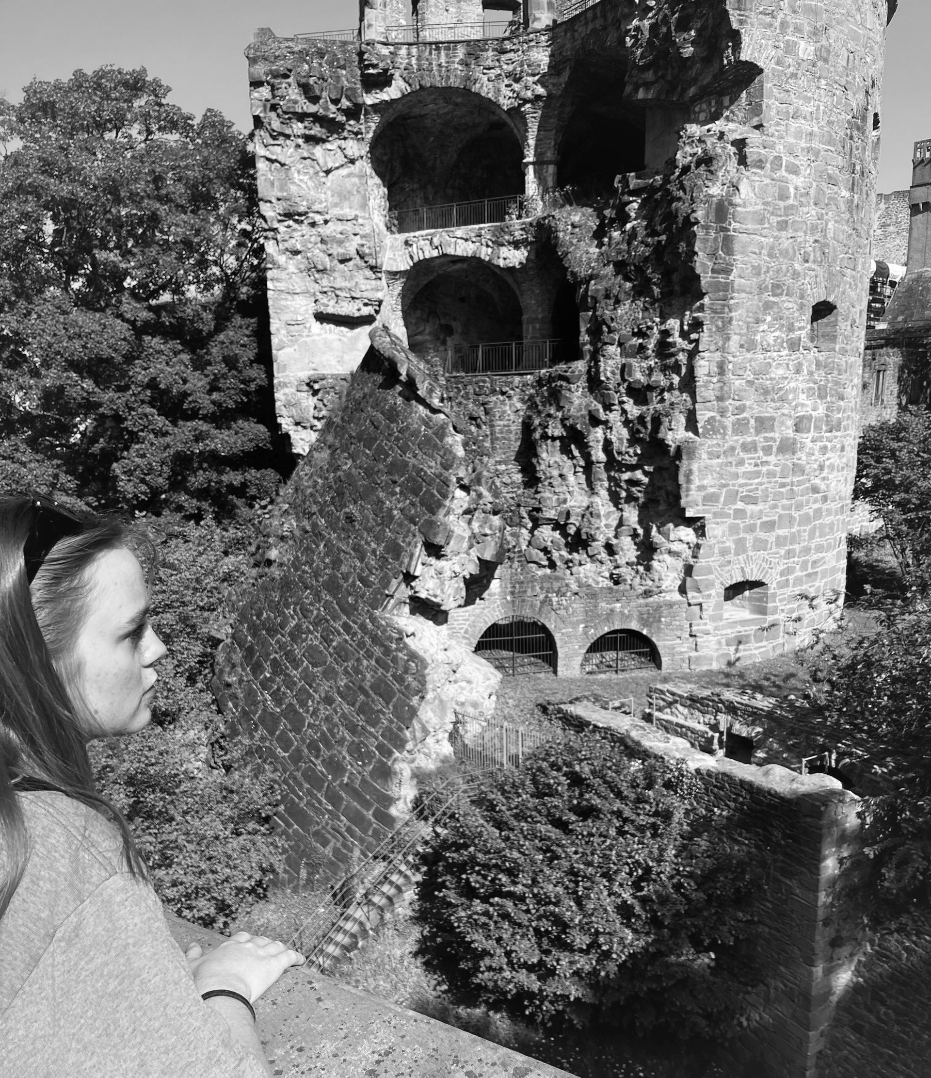 A woman is standing in front of a castle in a black and white photo.