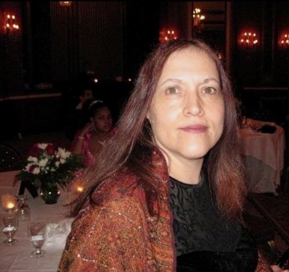 A woman sitting at a table with flowers and wine glasses