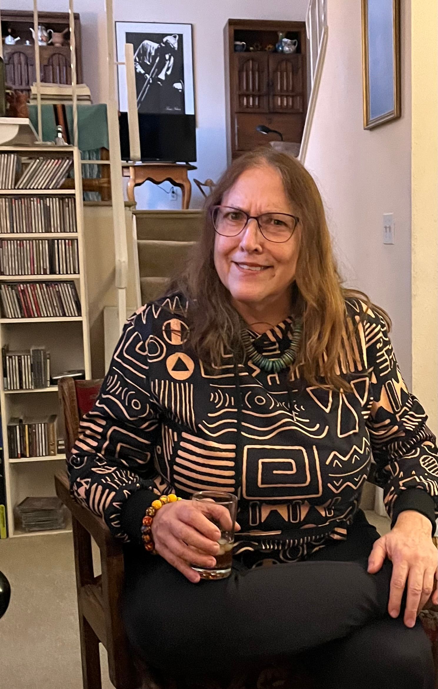 A woman is sitting in a chair in a living room holding a glass of wine.