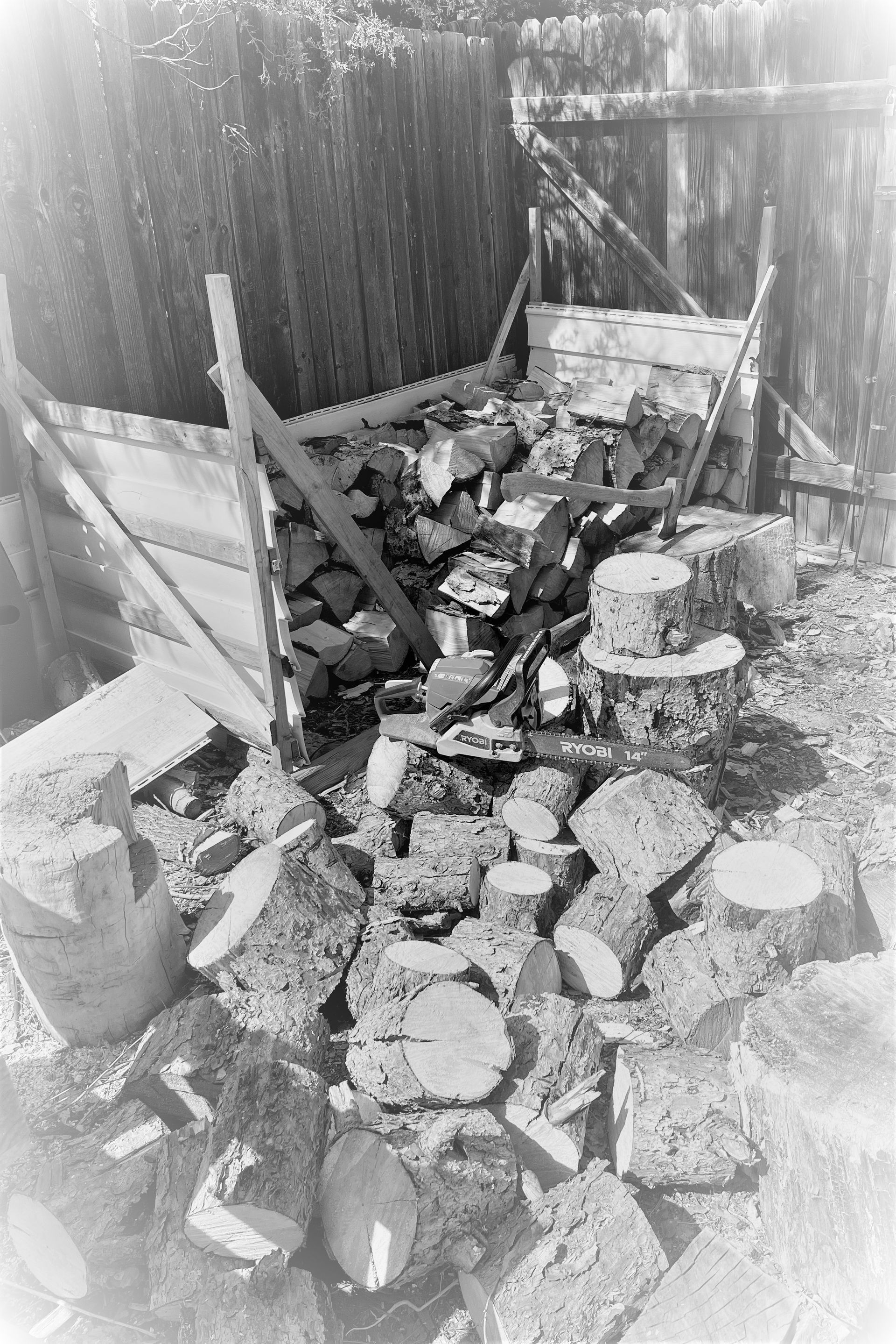 A black and white photo of a pile of rocks in front of a wooden fence.