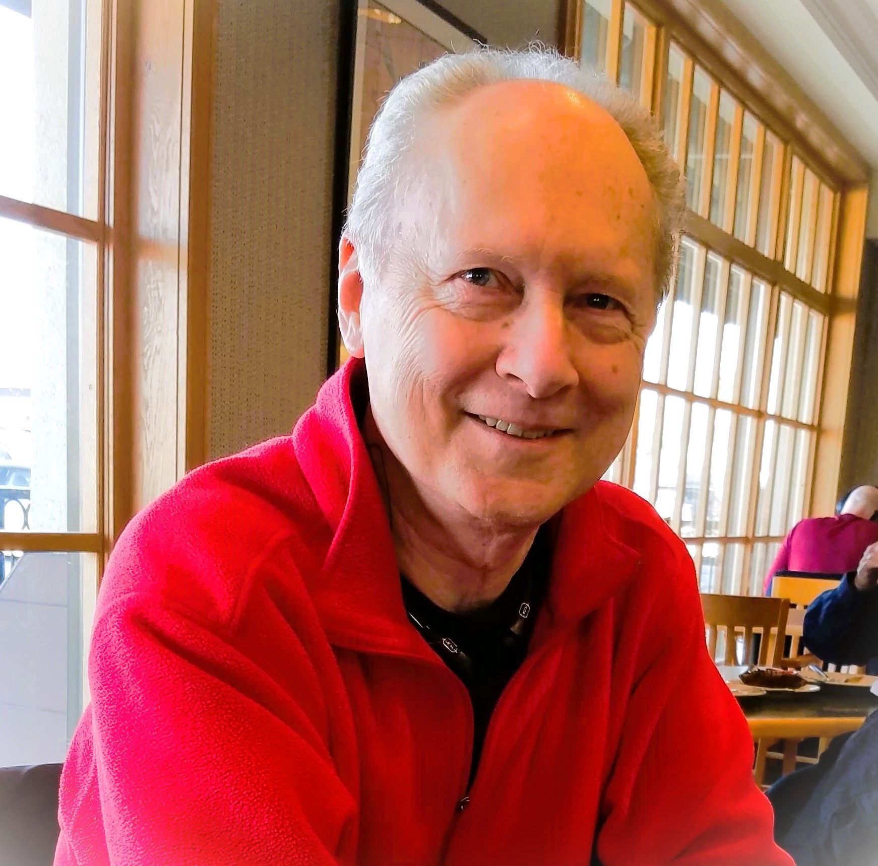 A man in a red jacket is smiling for the camera