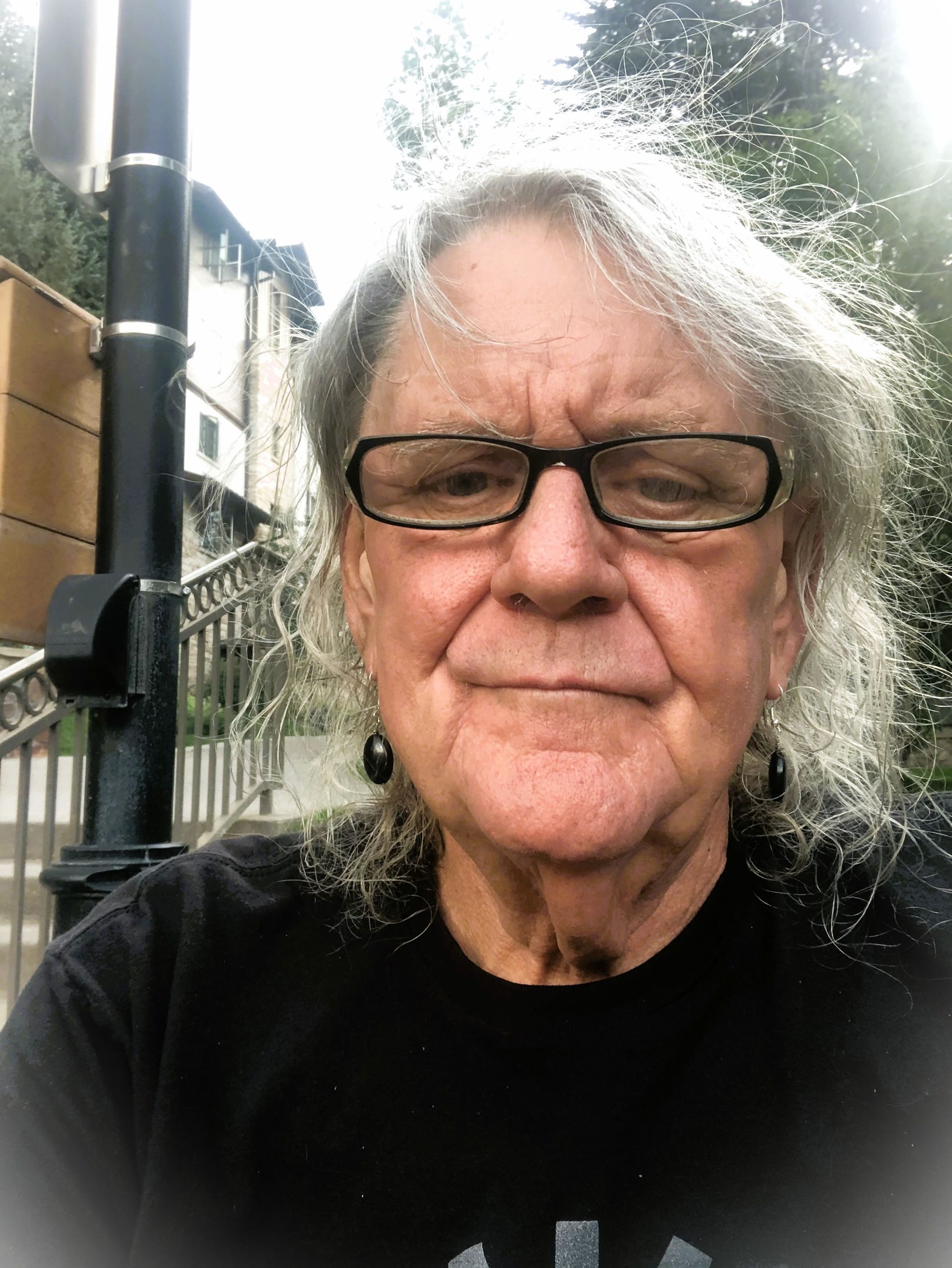 A man with long hair and glasses is taking a selfie.