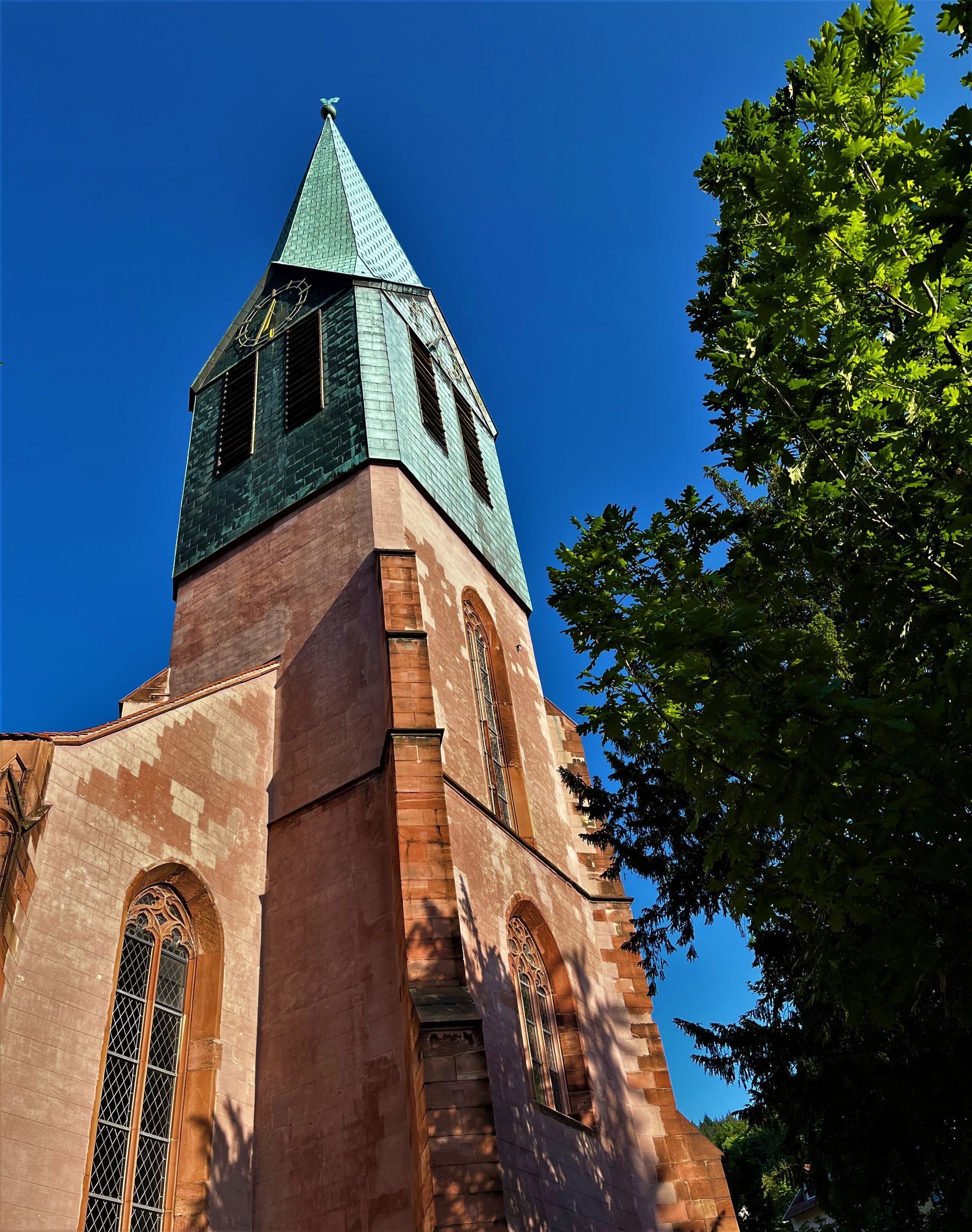 A church with a green steeple and a cross on top