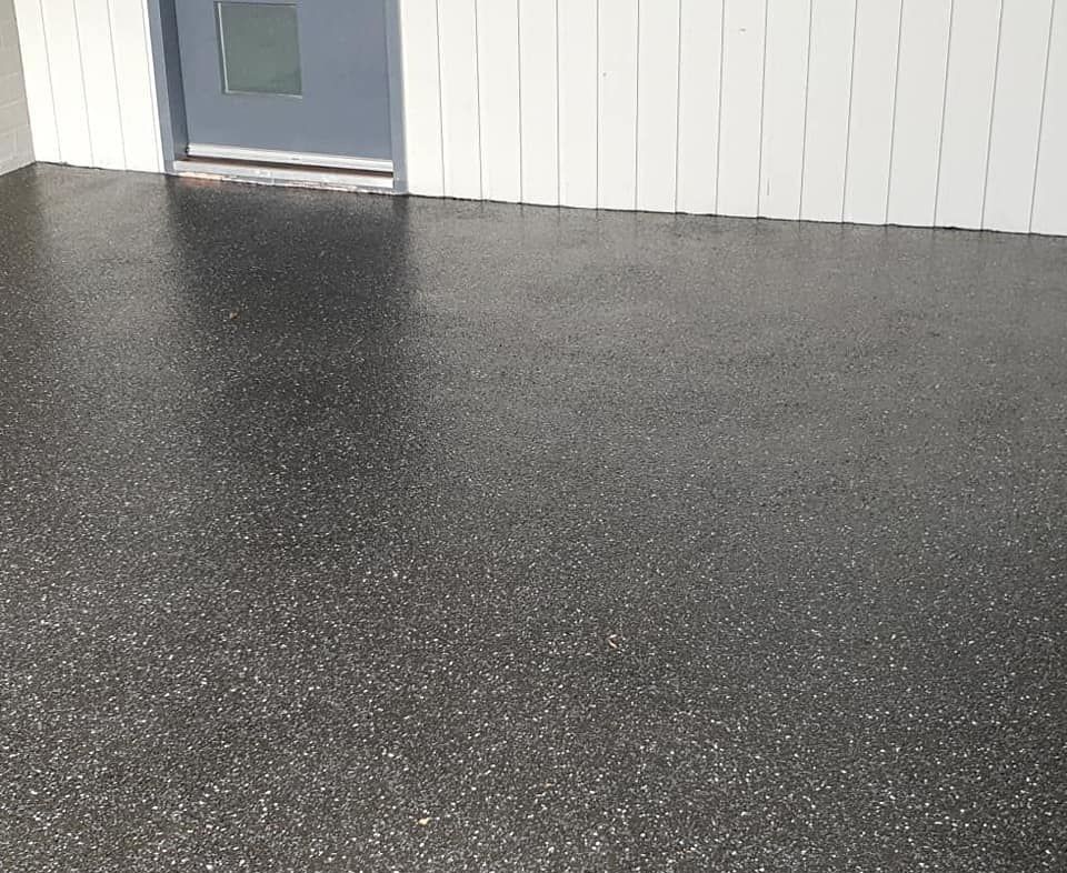 A Black Concrete Floor With A Door In The Background — Partlic Painting & Epoxy Flooring In Taree, NSW
