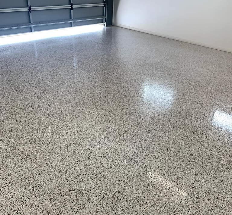 A Garage With A Shiny White Floor And A Garage Door — Partlic Painting & Epoxy Flooring In Taree, NSW
