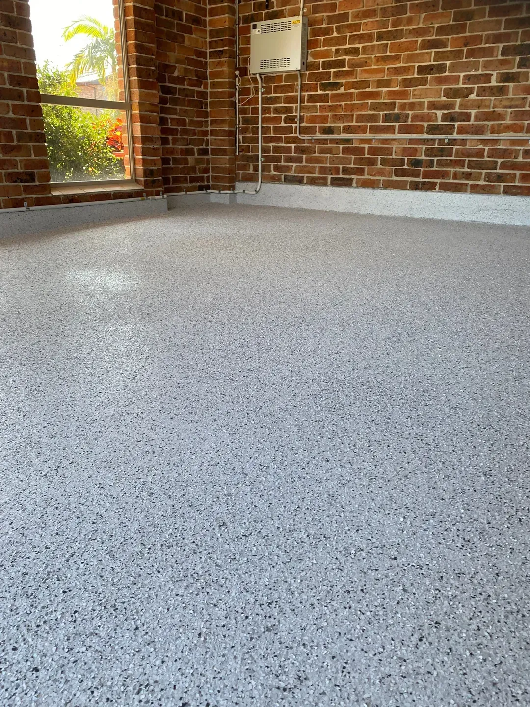A garage with a brick wall and a white floor. — Partlic Painting & Epoxy Flooring In Taree, NSW