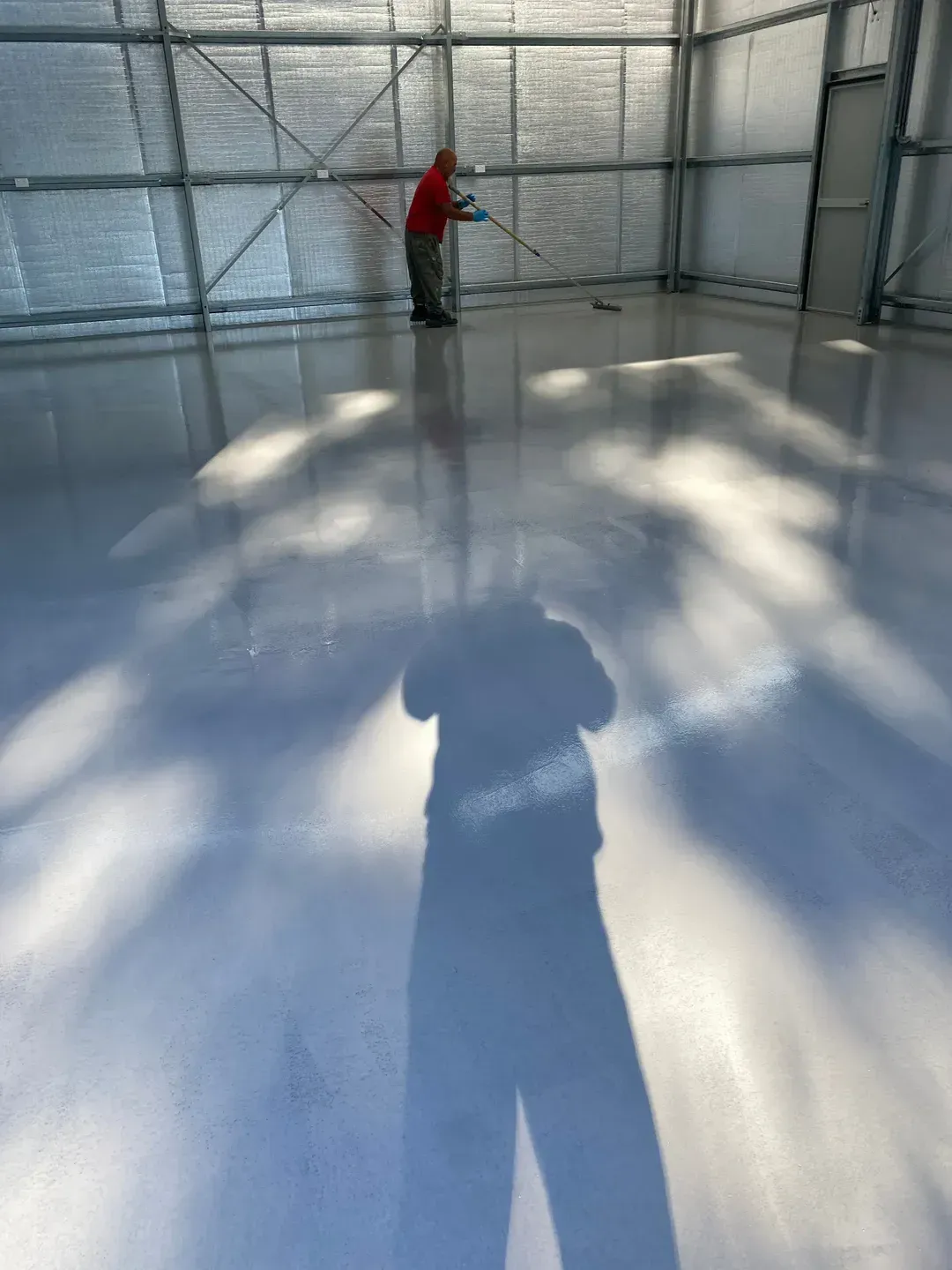 A Man Is Cleaning The Floor Of A Building With A Broom — Partlic Painting & Epoxy Flooring In Nabiac, NSW