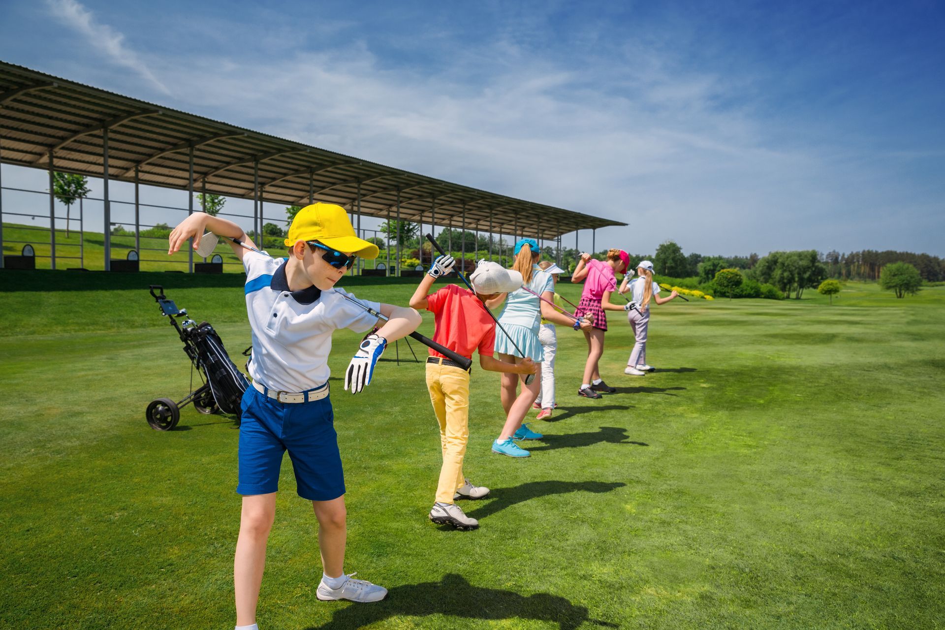 Golfers stretching on a green course near a covered practice area Golfers stretching on a green course near a covered practice area