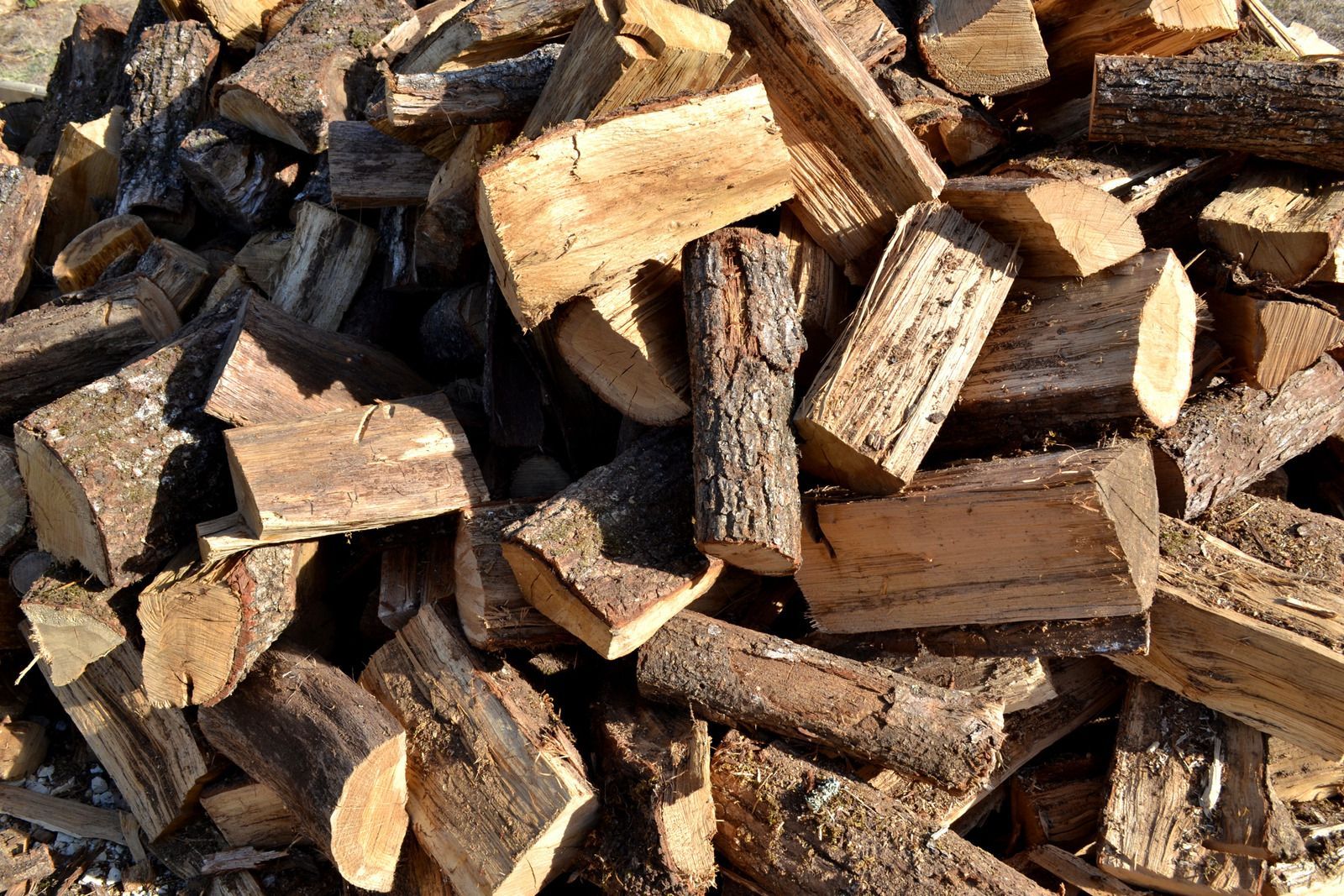 A pile of chopped wood is sitting on the ground.