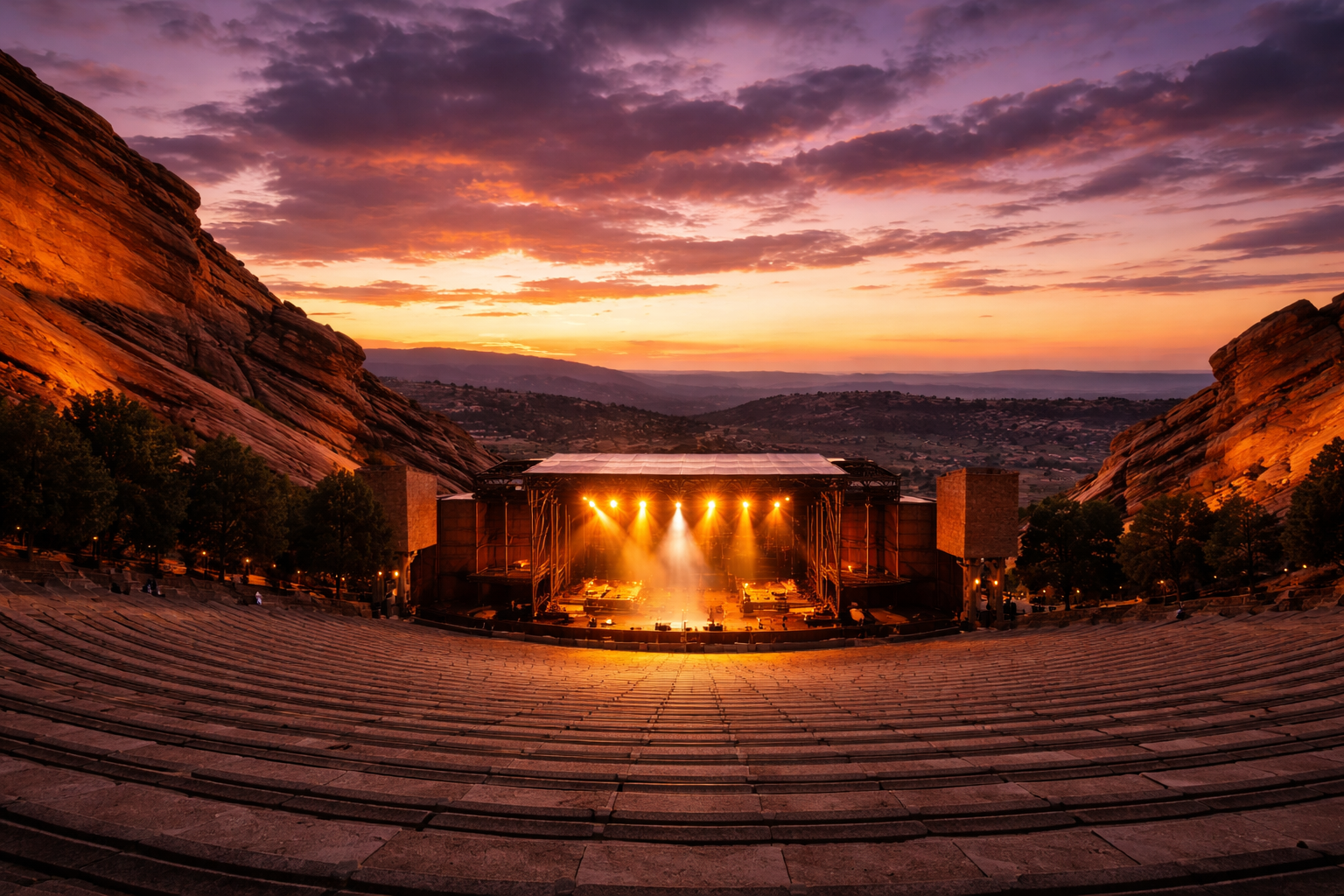 Red Rocks Amphitheatre at sunset with concert stage lights glowing and mountain silhouettes
