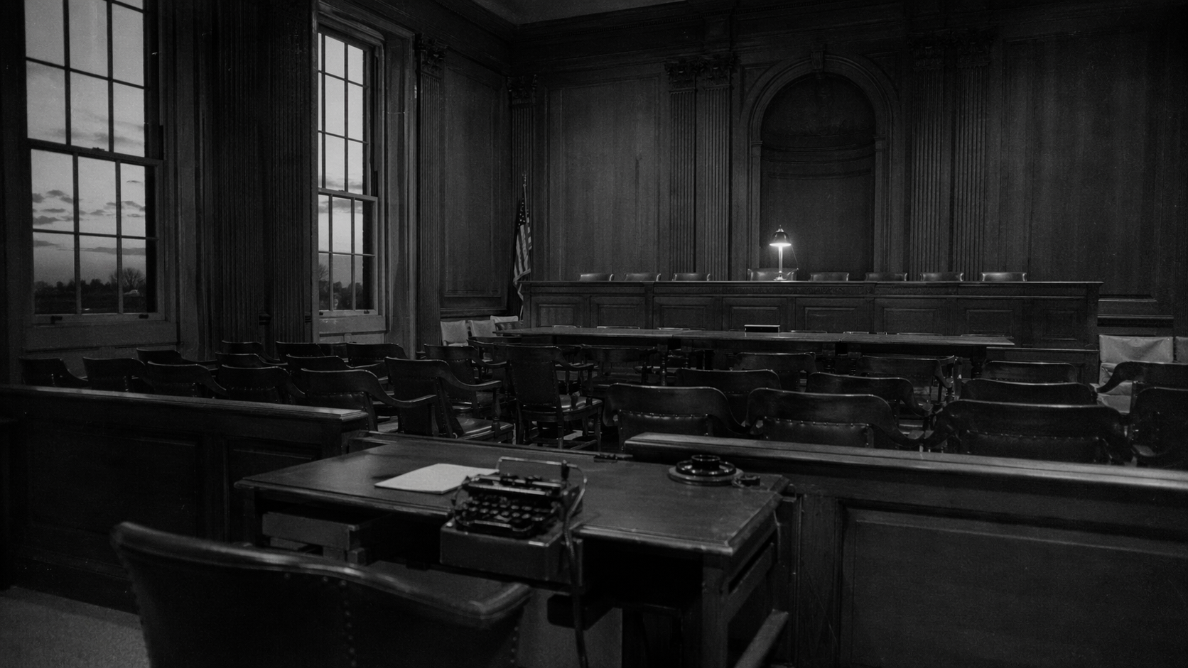 Black and white archival photograph of a congressional hearing room with empty wooden chairs