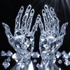 Crystal sculpture of two raised hands made of faceted diamond material with reflective light