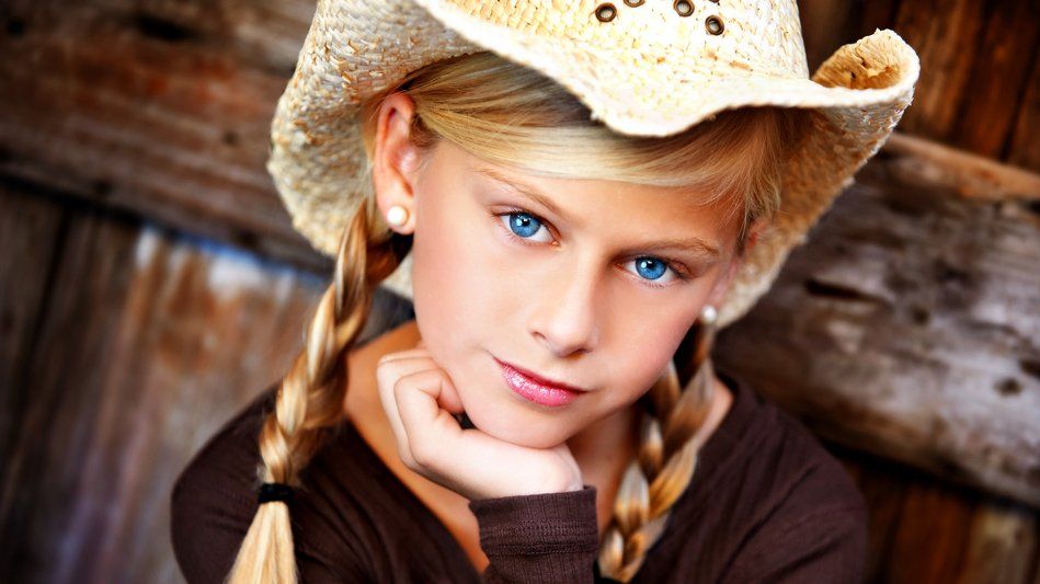 A little girl wearing a cowboy hat and braids.