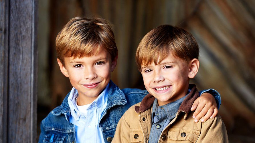 Two young boys are sitting next to each other and smiling for the camera.