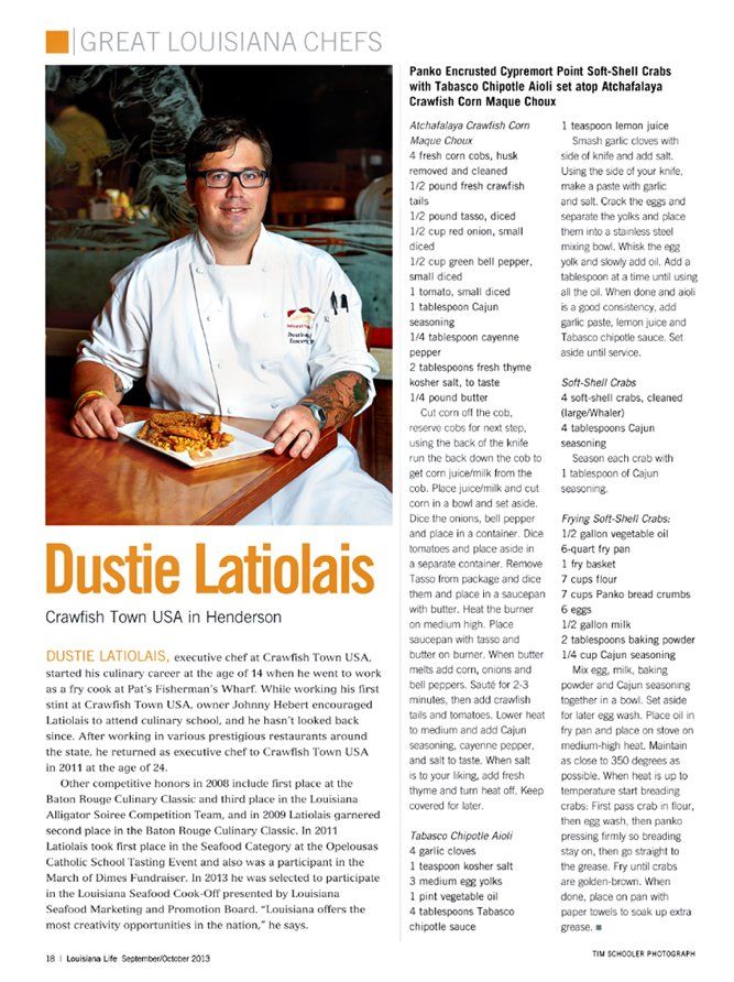 A chef is sitting at a table holding a plate of food.