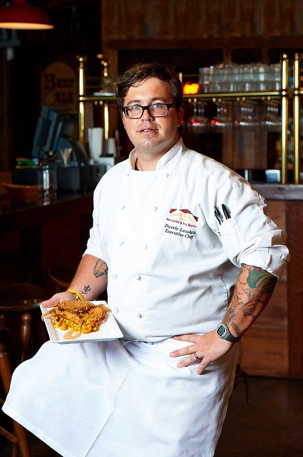 A man in a chef 's uniform is holding a plate of food.