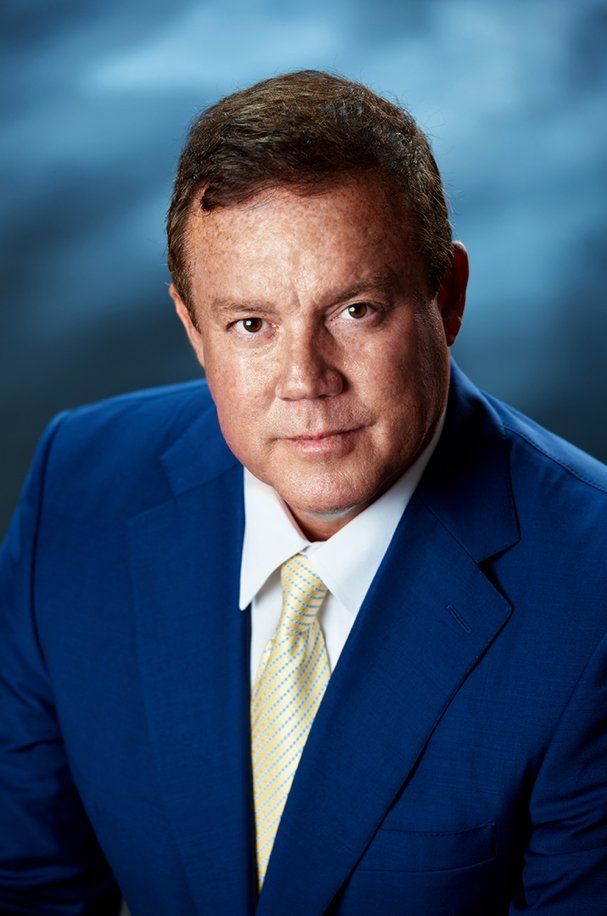 A man in a blue suit and tie is looking at the camera.