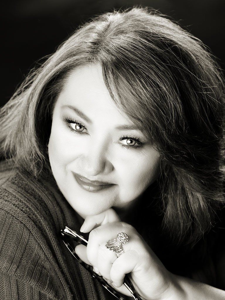 A woman wearing a ring on her finger is smiling in a black and white photo.