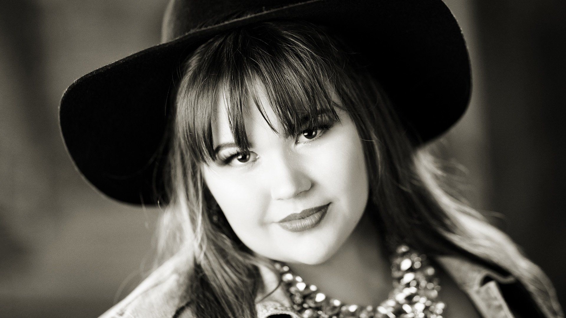 A black and white photo of a woman wearing a hat and a necklace.