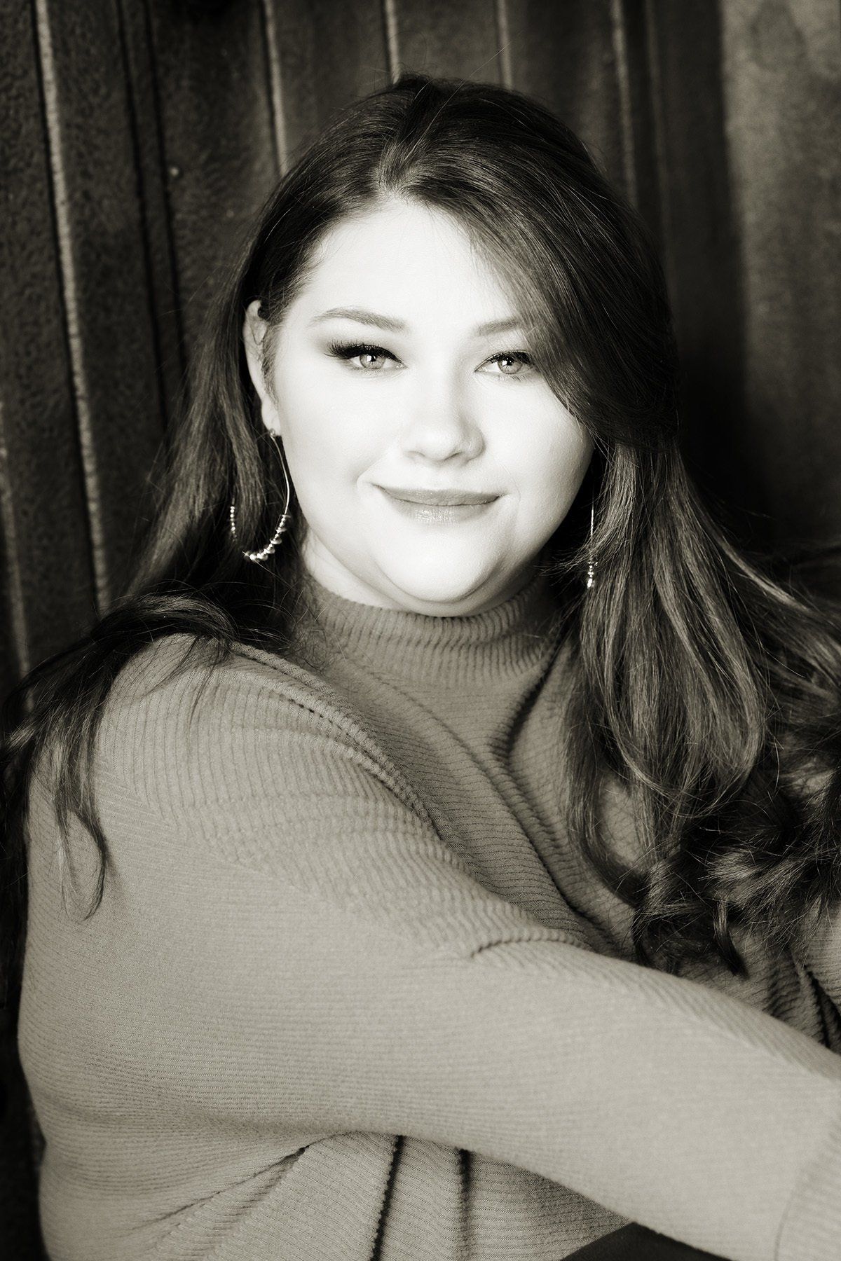 A woman with long hair is smiling in a black and white photo.
