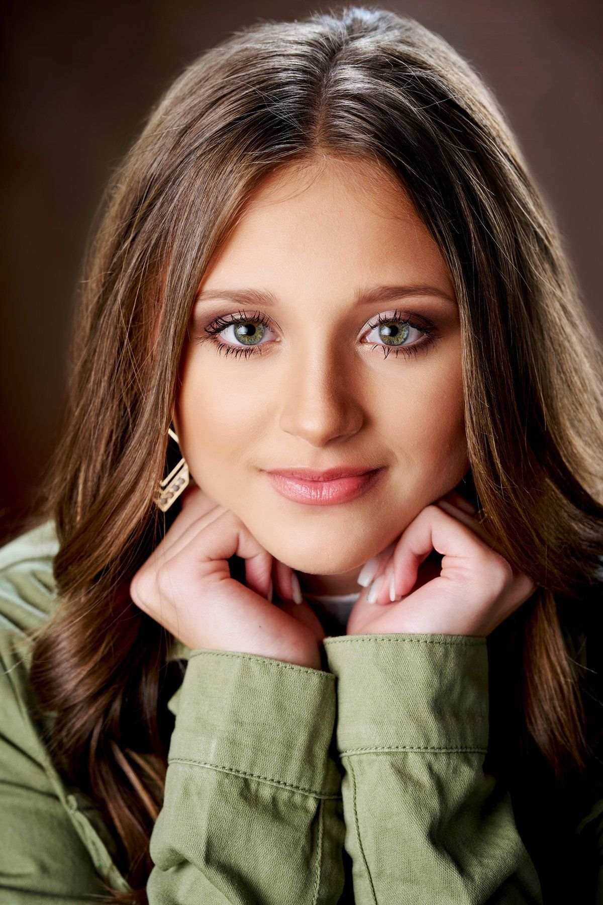 A close up of a woman 's face with her hands on her chin.