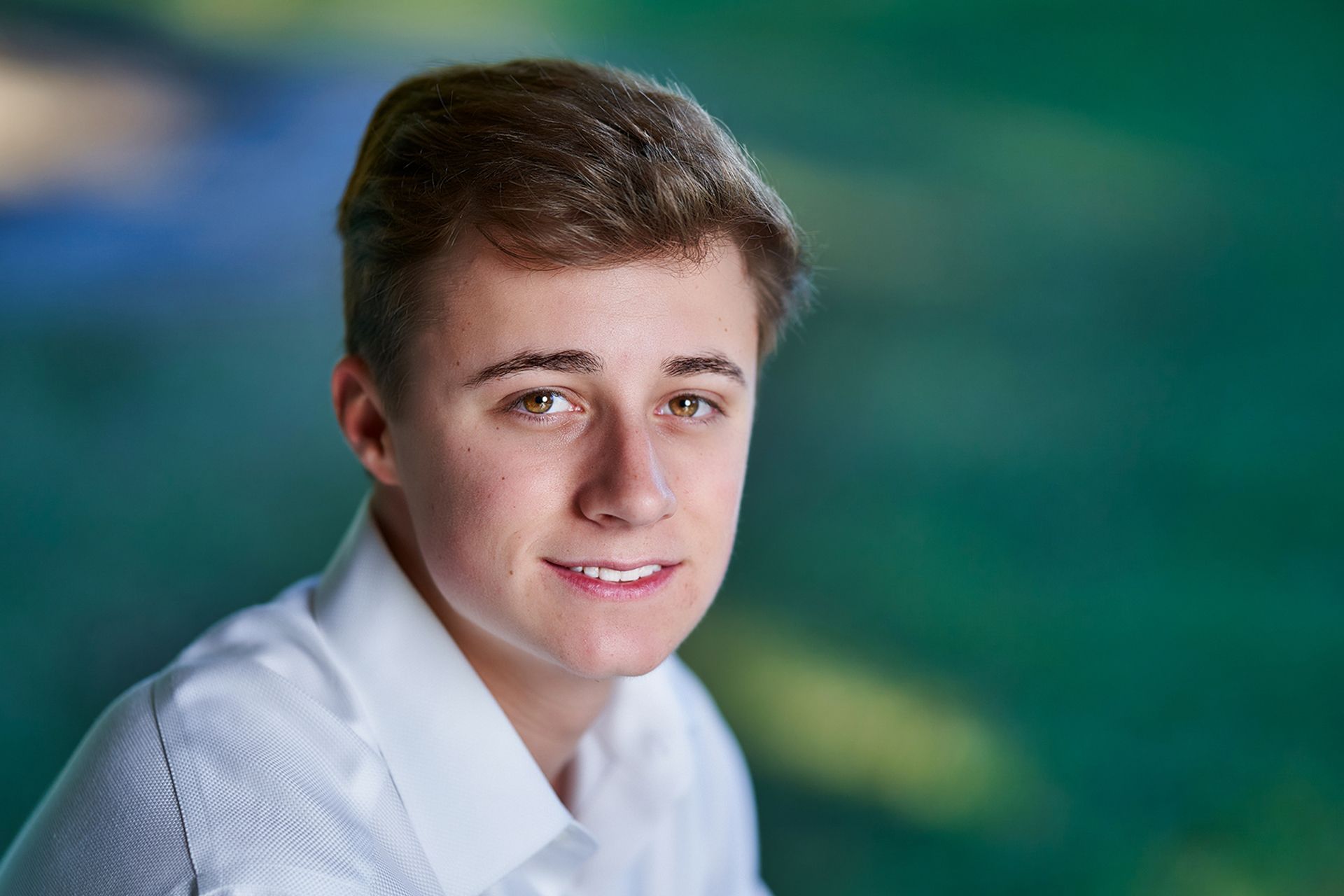 A young man in a white shirt is smiling for the camera.