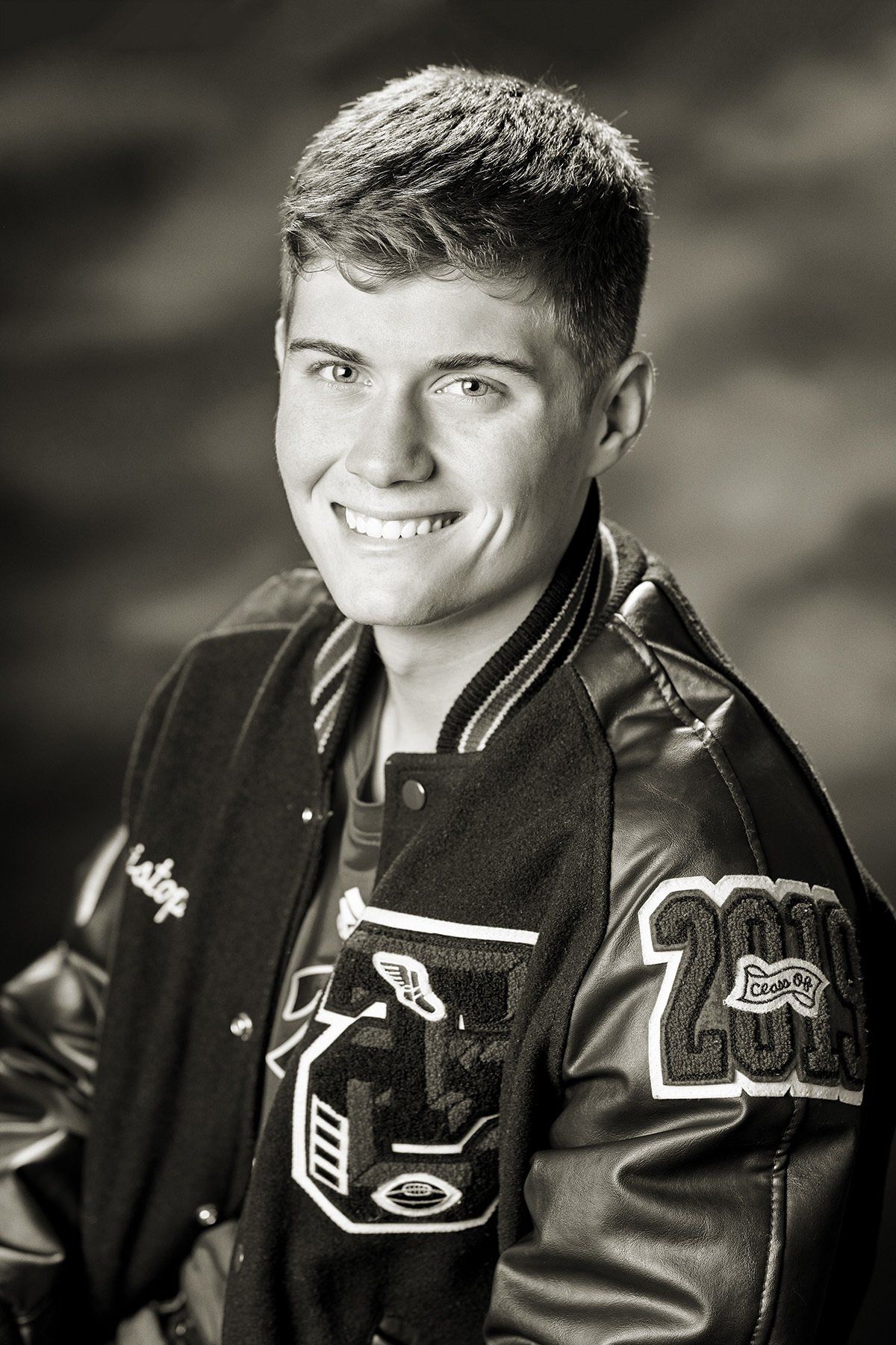 A black and white photo of a young man wearing a letterman jacket with the number 23 on the sleeves.