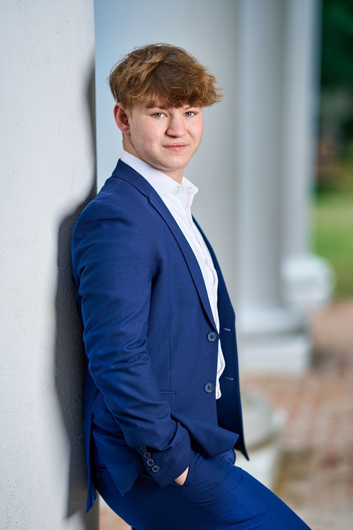 A young man in a green shirt is standing with his arms crossed