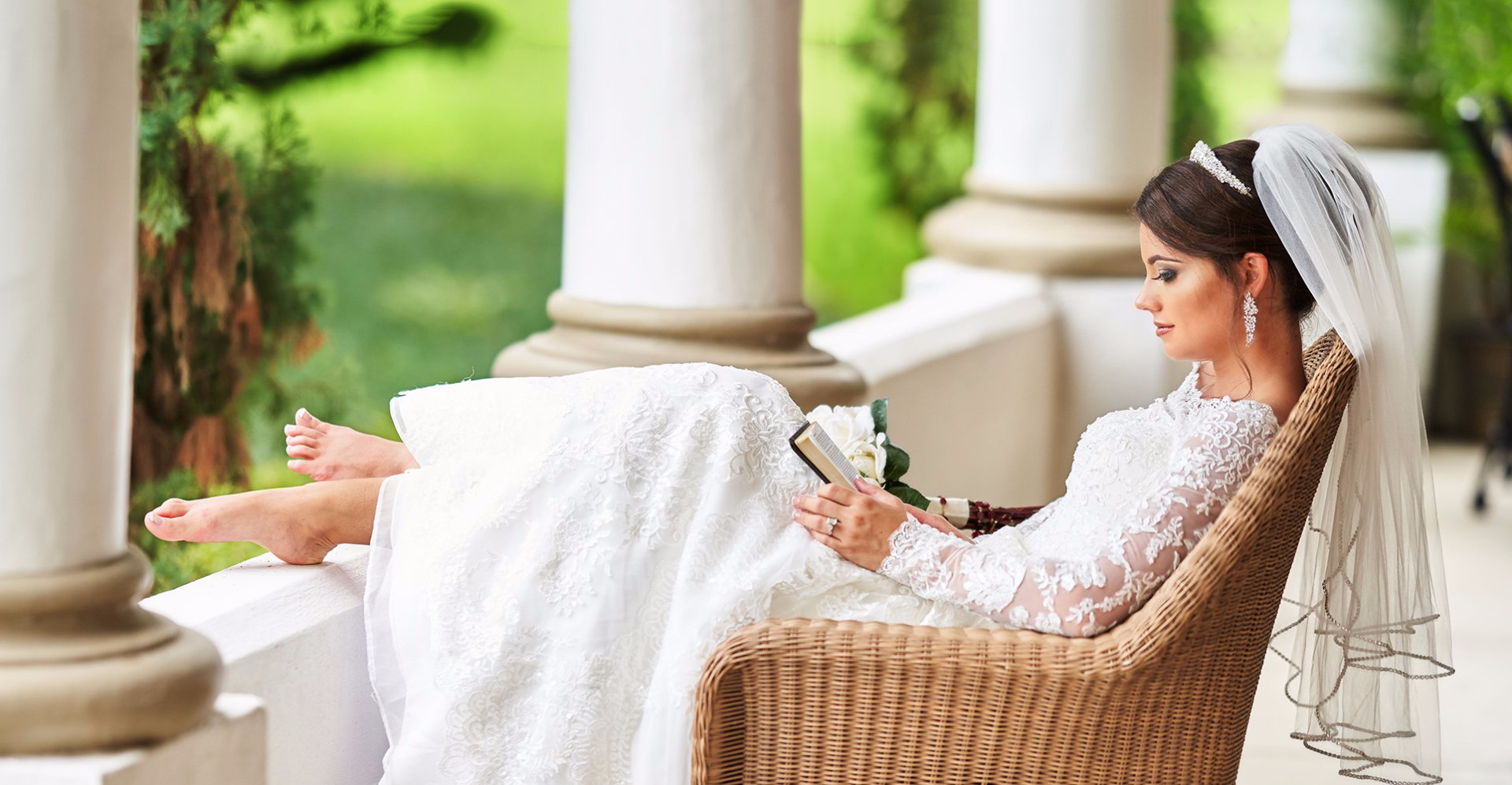 A bride in a wedding dress is sitting in a chair reading a book.