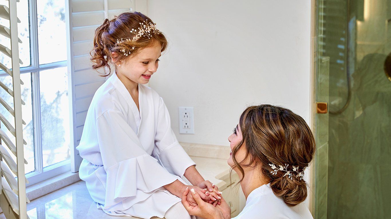 A woman and a little girl are sitting next to each other in front of a window.