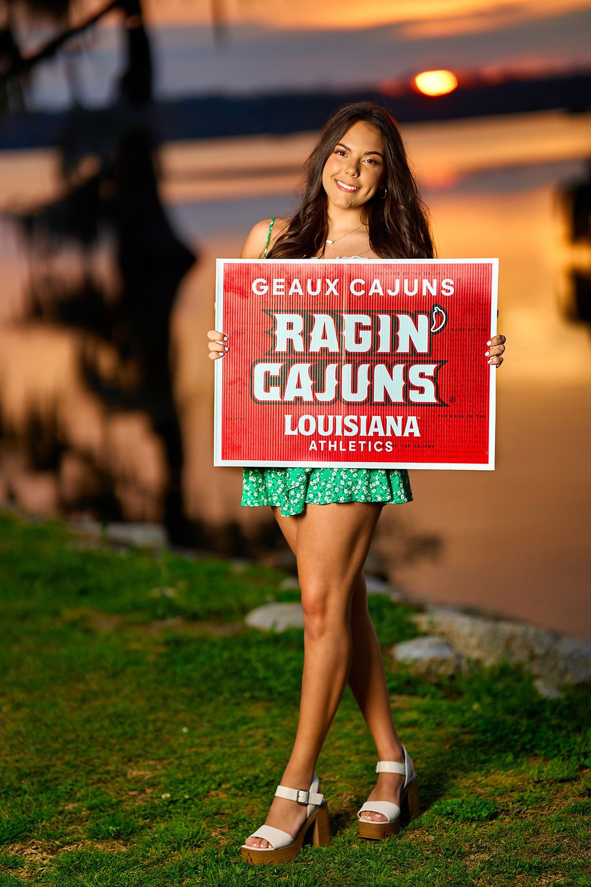A woman wearing a white sweater and blue jeans is sitting down with her hand on her chin.