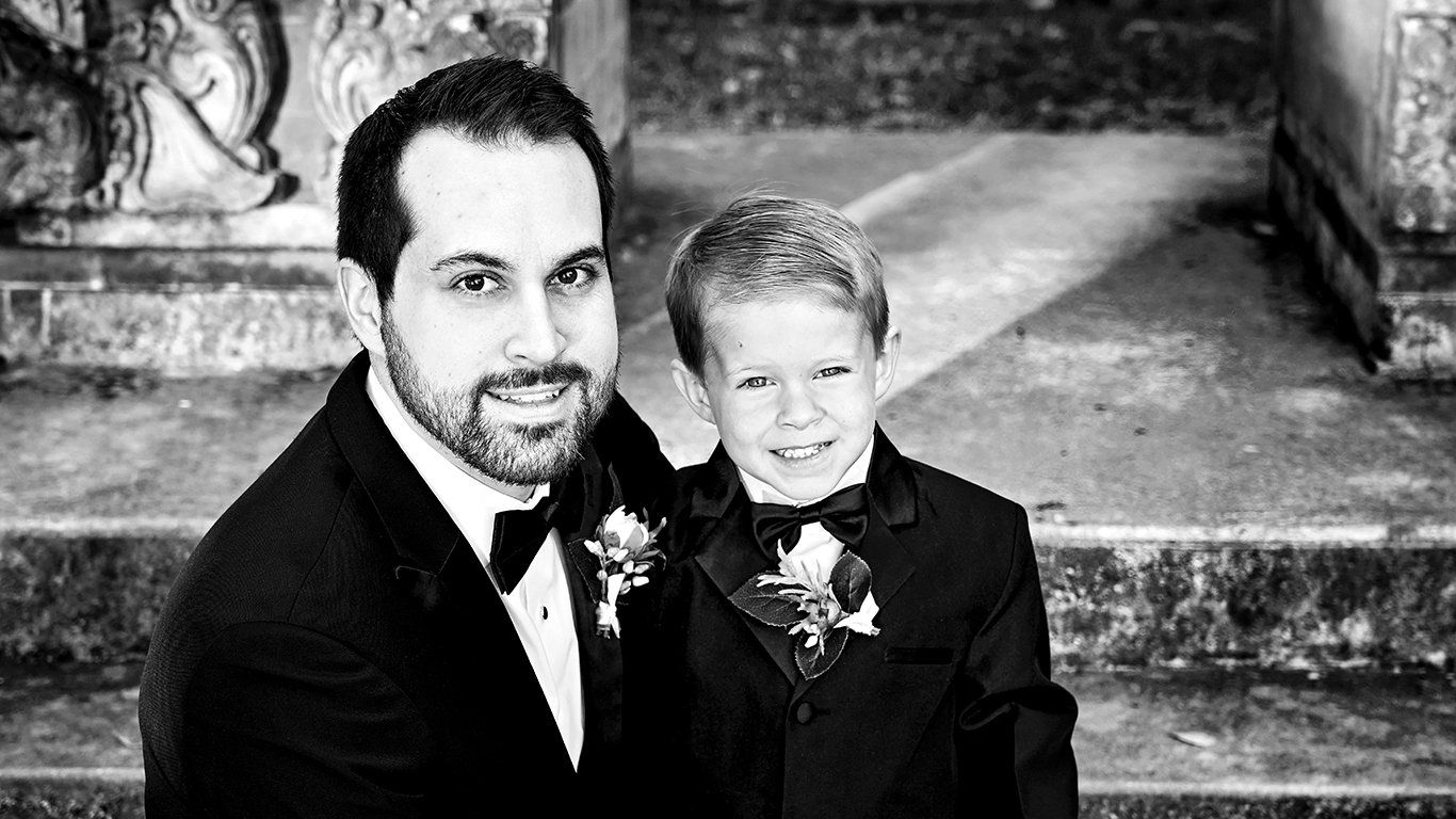 A man and a boy in tuxedos are posing for a picture.
