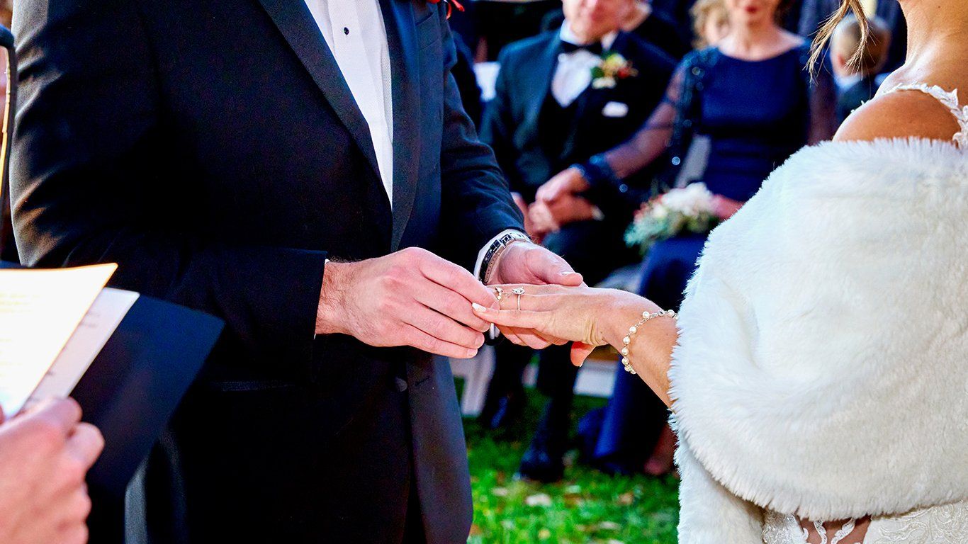 A man is putting a wedding ring on a woman 's finger.