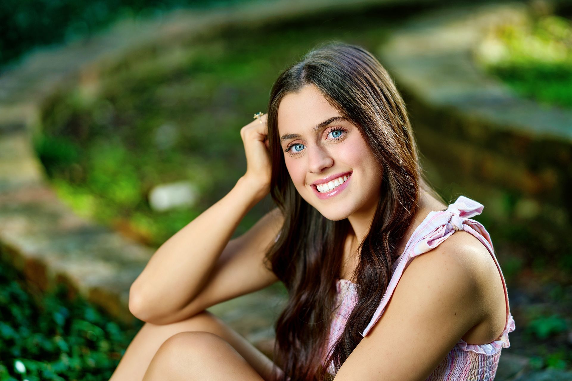 A young woman is sitting on the ground smiling for the camera.