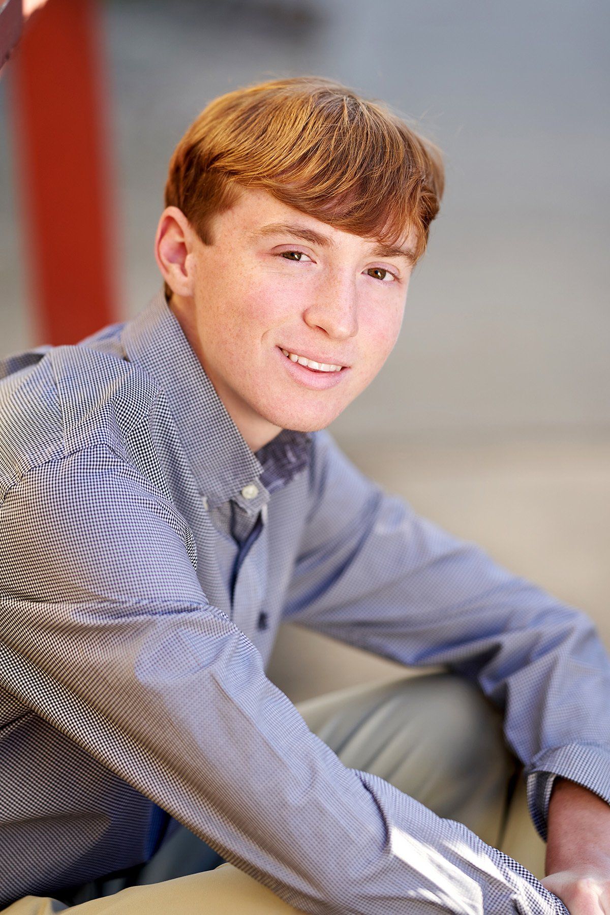 A young man in a blue shirt is sitting down and smiling.