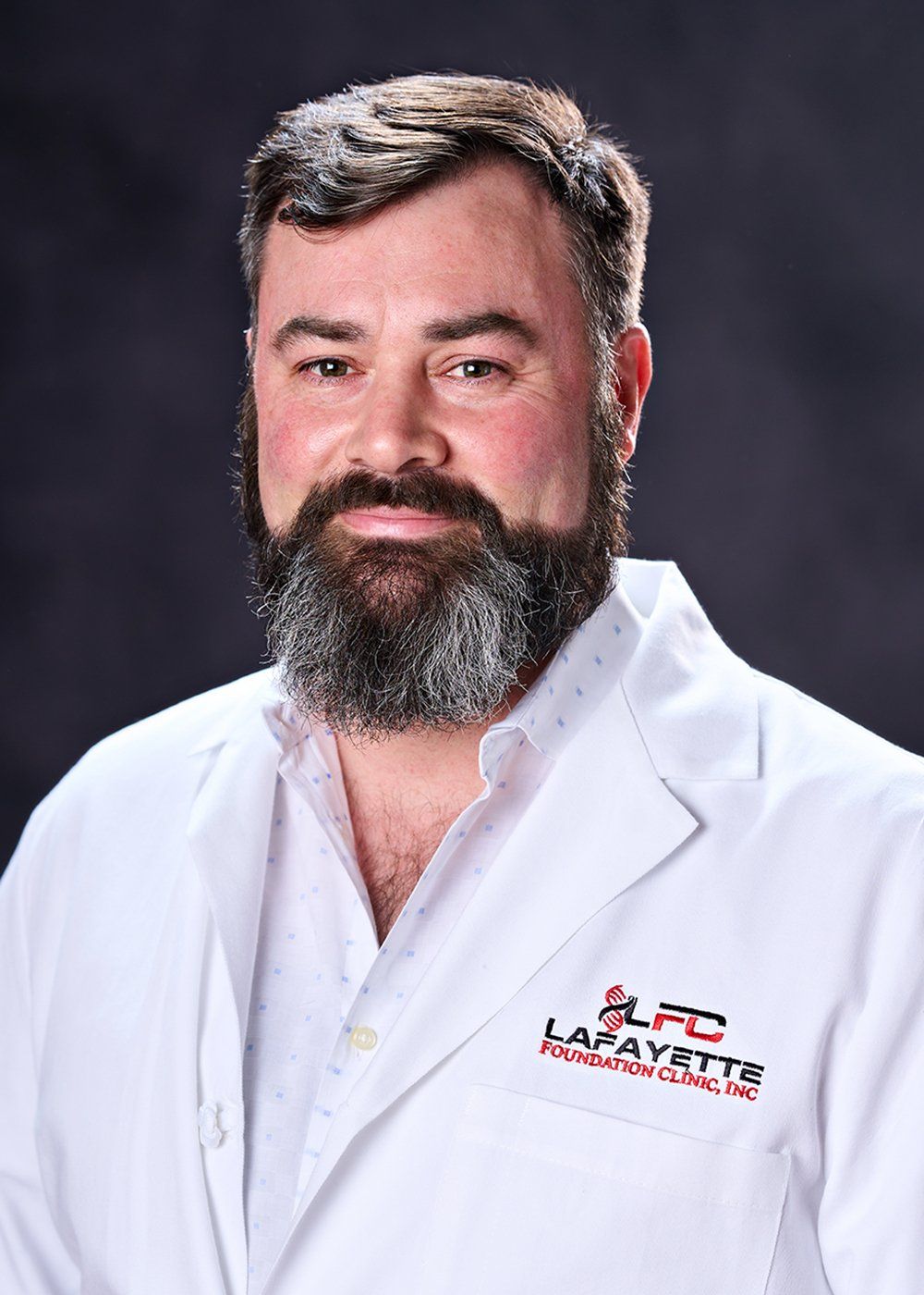 A man with a beard is wearing a white lab coat.